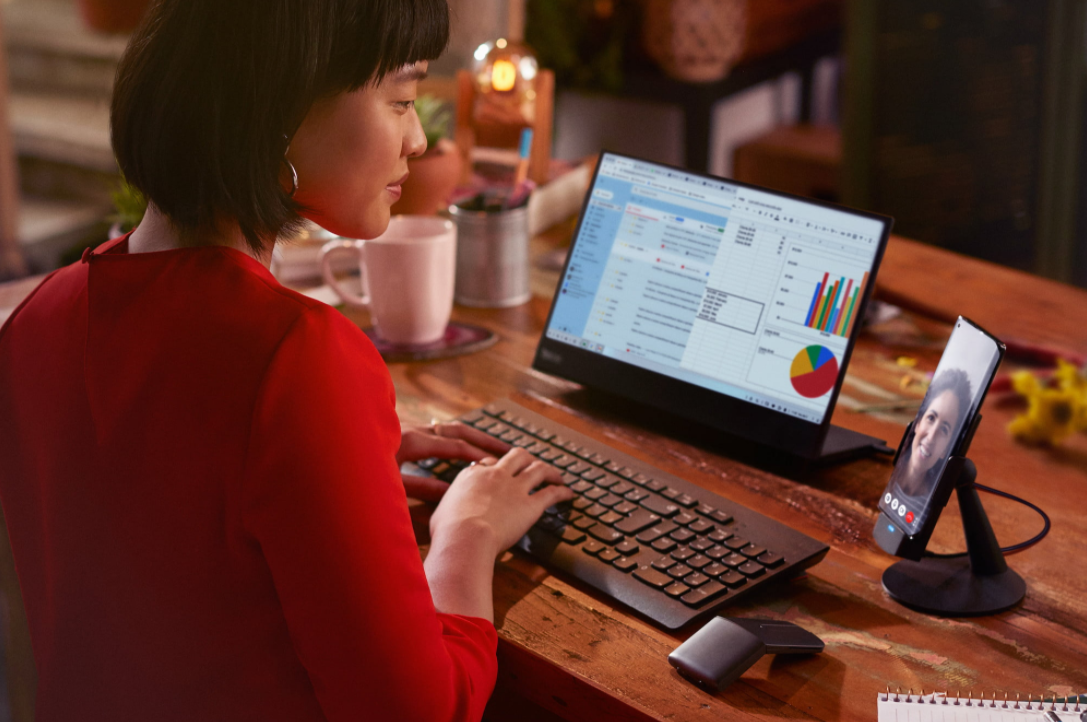 mulher usando o smartphone num monitor com teclado e mouse